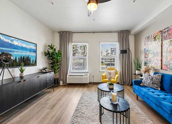 A living room with a blue couch, a television, and a painting on the wall.