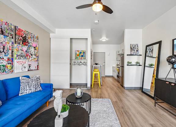 A living room with a blue couch, a coffee table, and a ceiling fan.