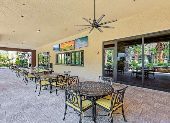 A patio with tables and chairs and a ceiling fan.