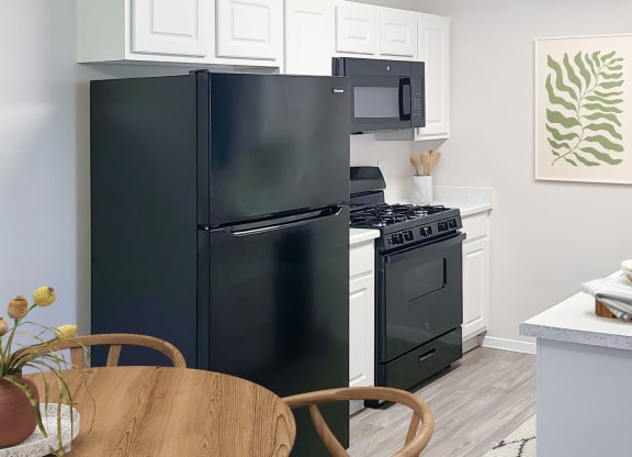 a kitchen with a black refrigerator freezer next to a stove top oven at Silver Creek Apartments, Las Vegas, Nevada