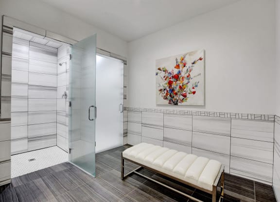 a white bathroom with a shower and a bench at Evoq Apartment Homes, Las Vegas, NV  