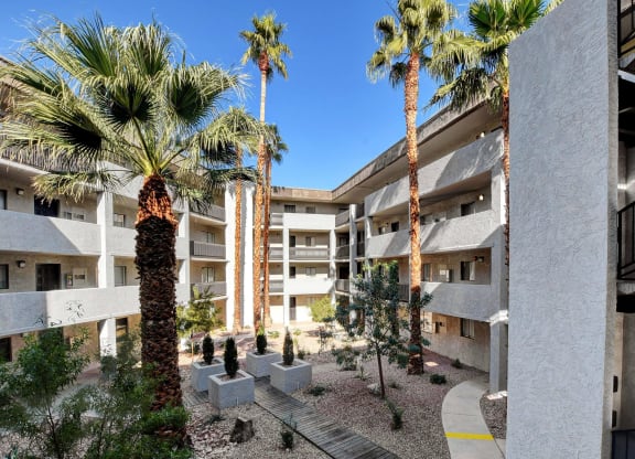 a view of a building with palm trees at Evoq Apartment Homes, Las Vegas, NV  