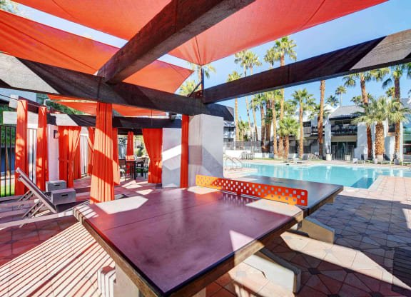 a patio with a pool and a table and chairs at Evoq Apartment Homes, Las Vegas, NV 89169  
