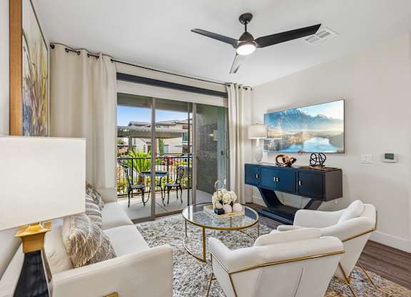 A living room with a white sofa, a glass coffee table, and a painting on the wall.