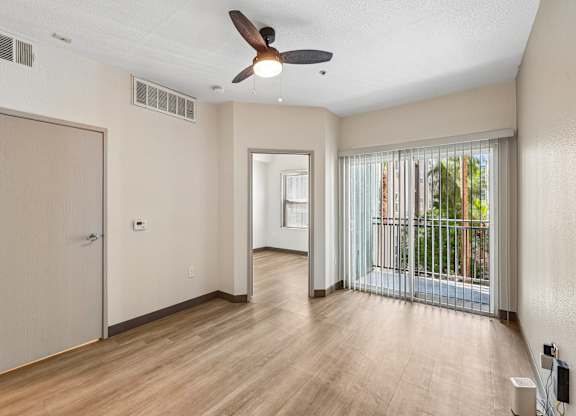 A room with a ceiling fan and sliding glass doors.