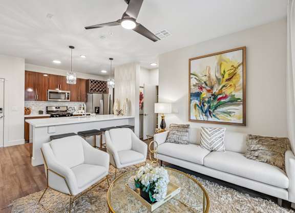 A living room with a white couch, a coffee table, and a painting on the wall.