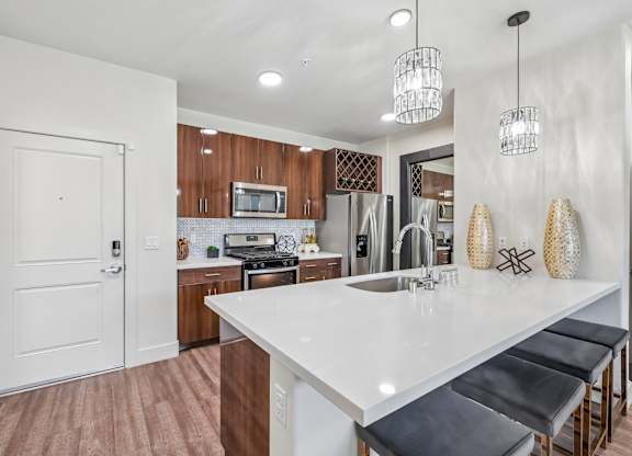 A kitchen with a white countertop and black bar stools.