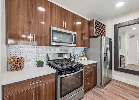 A kitchen with wooden cabinets and a stainless steel refrigerator.