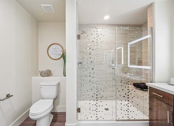 A white toilet sits in a bathroom with a glass shower stall.