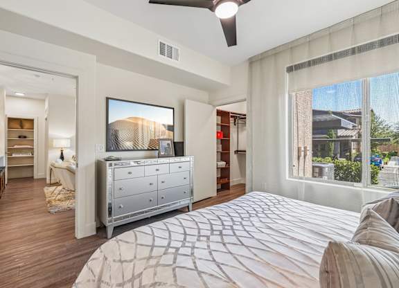 A bedroom with a large bed and a television on the wall.