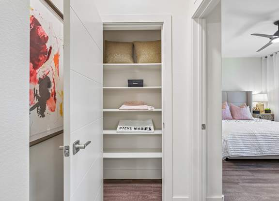 A white door with a painting on the left and a bedroom on the right.