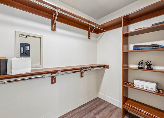 A room with a white wall and a brown shelf.