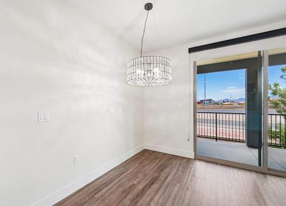 A room with a wooden floor and a sliding glass door leading to a balcony.