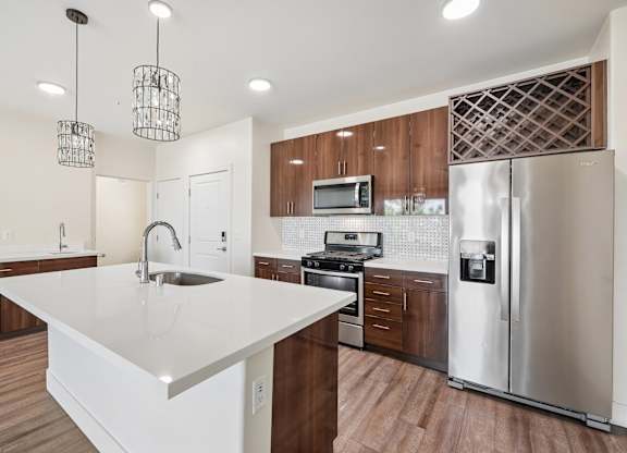 A modern kitchen with a white countertop and stainless steel appliances.
