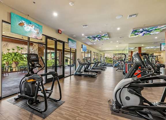 A gym with treadmills, elliptical machines, and other exercise equipment.