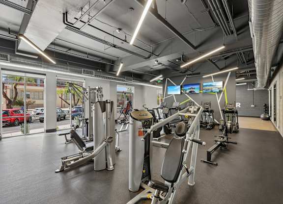 A gym with a variety of equipment including treadmills, stationary bikes, and weight machines.