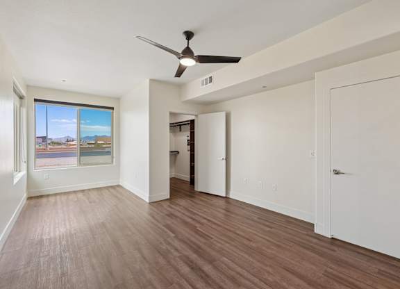 A room with a ceiling fan and wooden flooring.