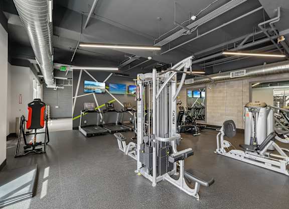 A gym with a variety of equipment including treadmills, weights, and exercise machines.