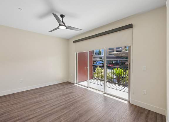 A room with a ceiling fan and sliding glass doors.