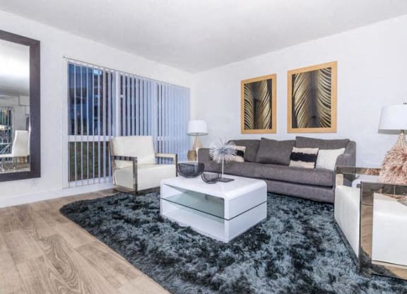 a living room with white furniture and a blue rug at Evoq Apartment Homes, Las Vegas  