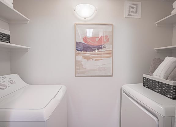 a white laundry room with a painting and a washer and dryer at Austin Crest Apartments, Nevada