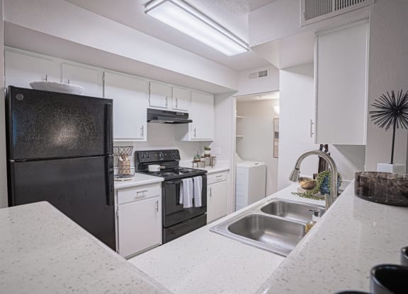 a kitchen with white cabinets and a black refrigerator at Austin Crest Apartments, Reno, NV
