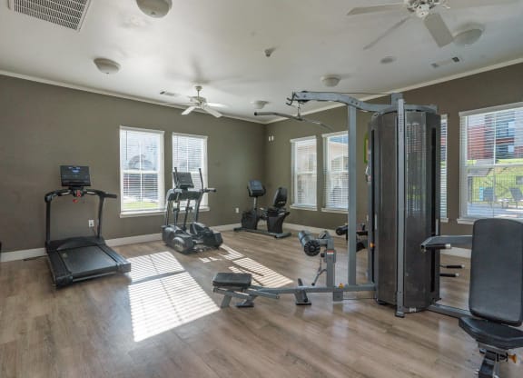 a gym with exercise equipment and windows in a home with wood floors at Austin Crest Apartments, Reno, 89523