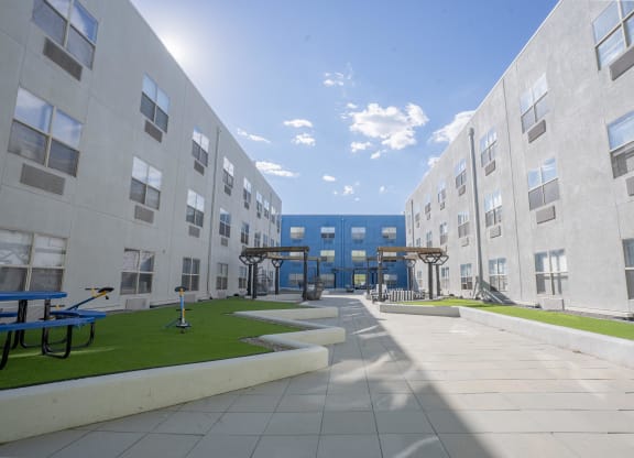 an exterior view of an apartment building with grass and benches  at The Onyx at 695, Reno