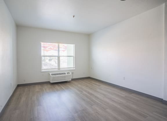 the living room of an empty house with wooden floors and a window at The Onyx at 695, Reno, NV