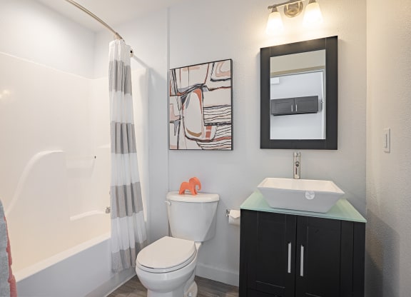 a bathroom with a toilet sink and mirror and a shower at ParcOne60, Reno, 89501