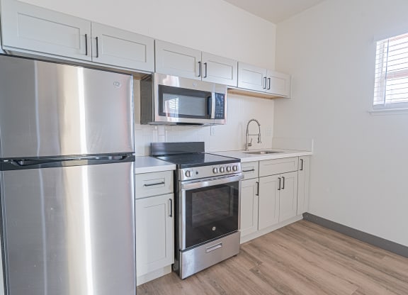 an empty kitchen with stainless steel appliances and white cabinets at ParcOne60, Reno, NV, 89501