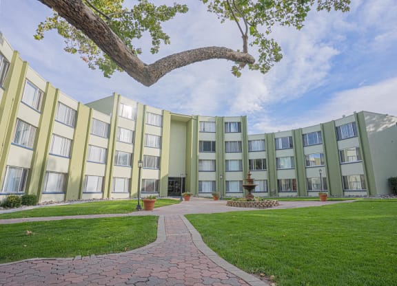a courtyard in front of an apartment building with green grass and a tree at Regency Park, Reno, 89509