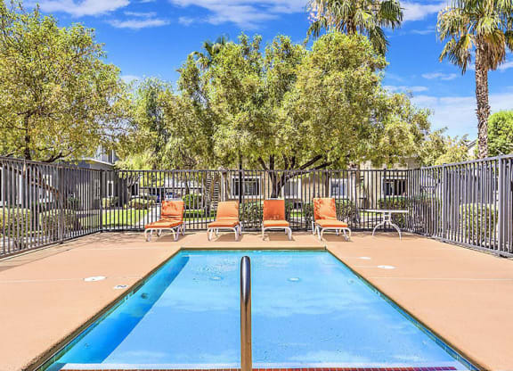 a swimming pool with chairs and a fence at Silver Creek Apartments, Las Vegas, 89122