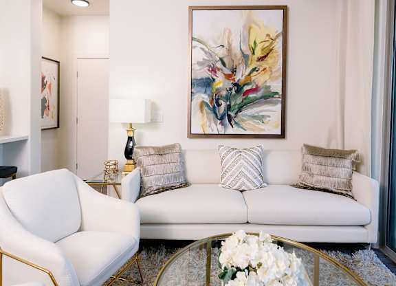 A white sofa with a gold frame and a white chair with a gold frame in a living room.