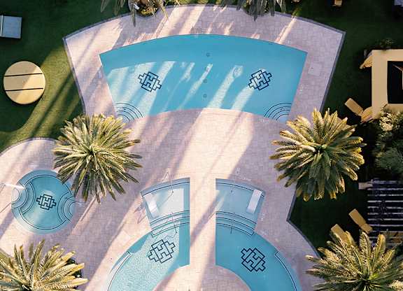 A pool surrounded by palm trees and a sign that says "Village".