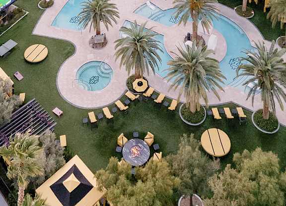 A pool surrounded by palm trees and a patio area.