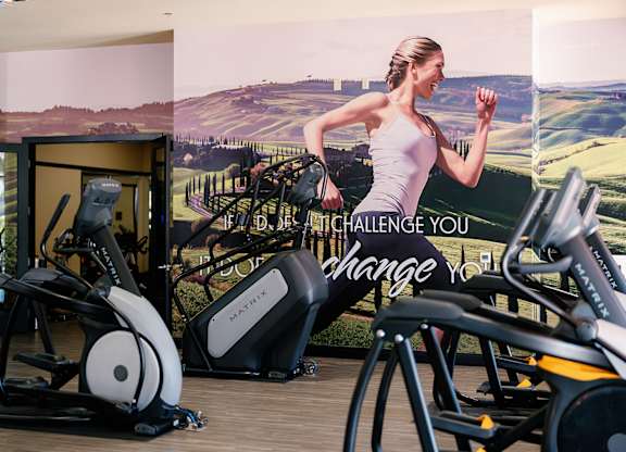 A woman is running on a treadmill in a gym.