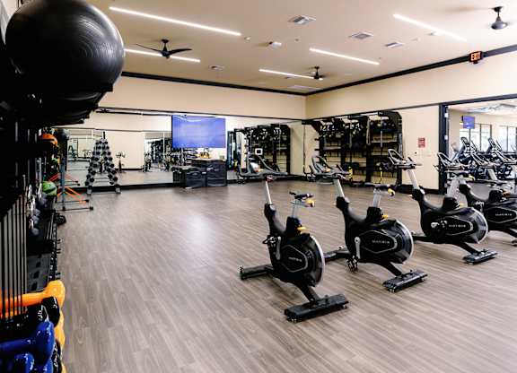A gym with a variety of exercise equipment including stationary bikes and weight racks.