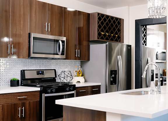 A kitchen with a white counter top and a stove top oven.