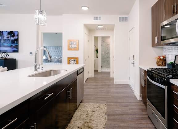 A modern kitchen with dark wood cabinets and stainless steel appliances.