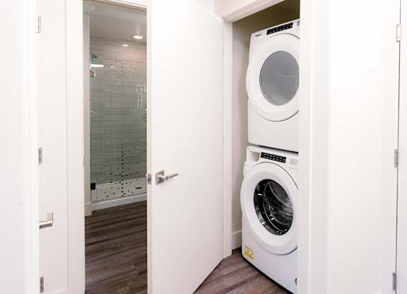A white washing machine is in a small white closet.