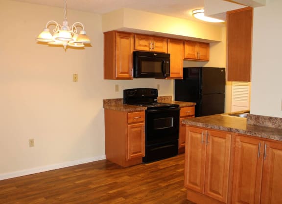 a kitchen with wooden cabinets and black appliances at Monroeville Apartments, Monroeville, PA, 15146