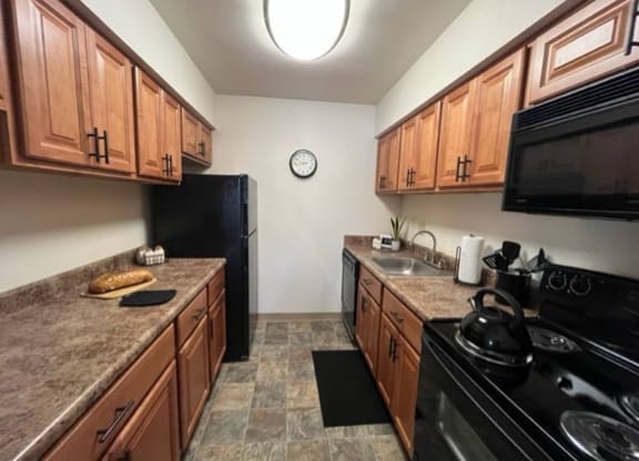 a kitchen with a stove top oven next to a refrigerator at Monroeville Apartments, Monroeville, PA