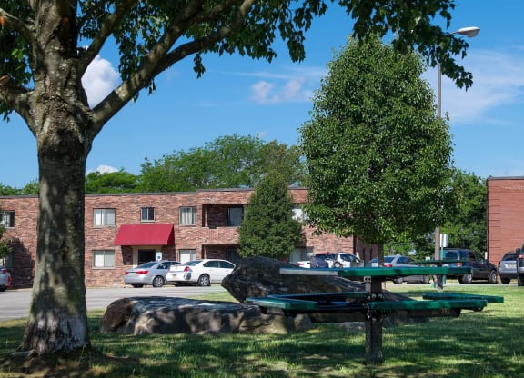a picnic table under a tree in front of a brick building at Monroeville Apartments, Monroeville