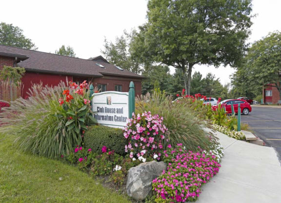a building with a sign and flowers in front of it at Monroeville Apartments, Monroeville, Pennslyvania