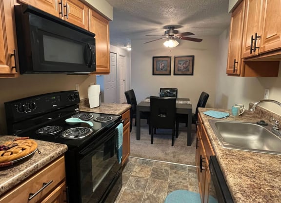 a kitchen with a stove top oven next to a sink at Monroeville Apartments, Pennslyvania
