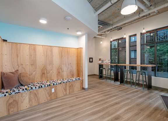 A room with a long wooden bench and a bar area.