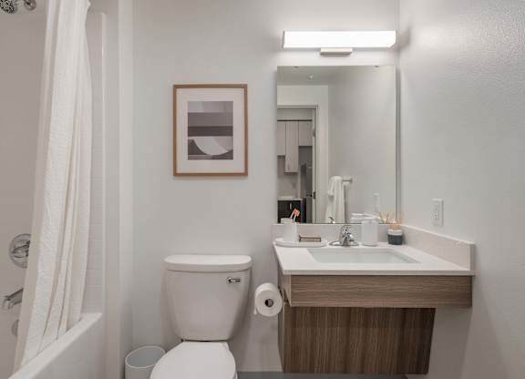 A bathroom with a toilet, sink, and mirror at Nook at Northaven Apartments, Seattle