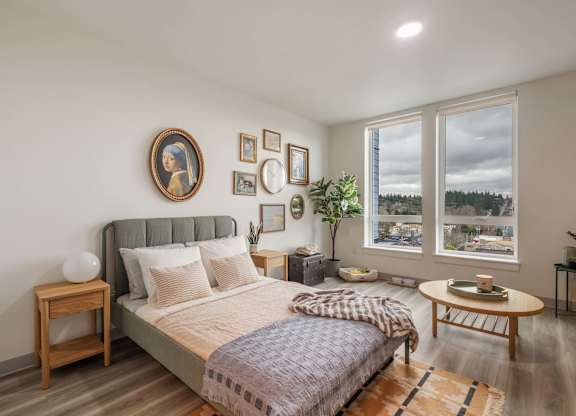 A bedroom with a large bed and a view of the outdoors through the window at Nook at Northaven Apartments, Washington 98125