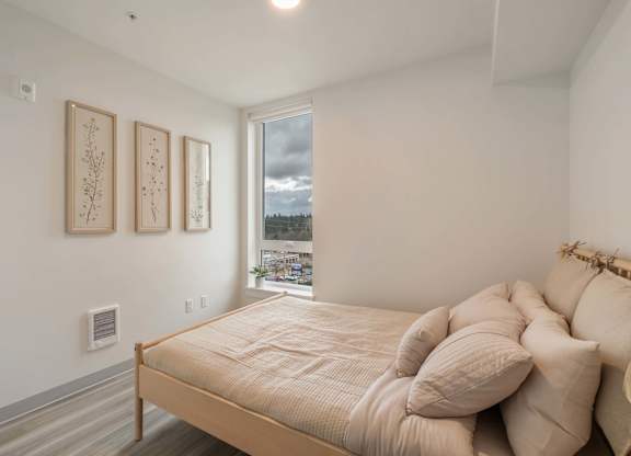A bedroom with a bed, pillows, and pictures on the wall at Nook at Northaven Apartments, Seattle